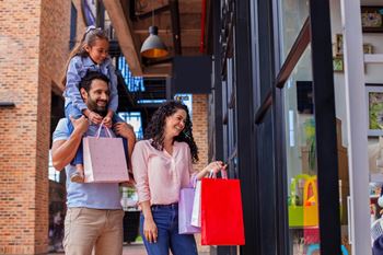 A family of three, a man, a woman and a child, are shopping together.